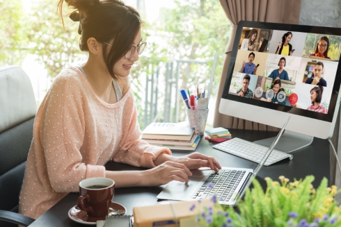 A woman working at a laptop while on a video conference with a team