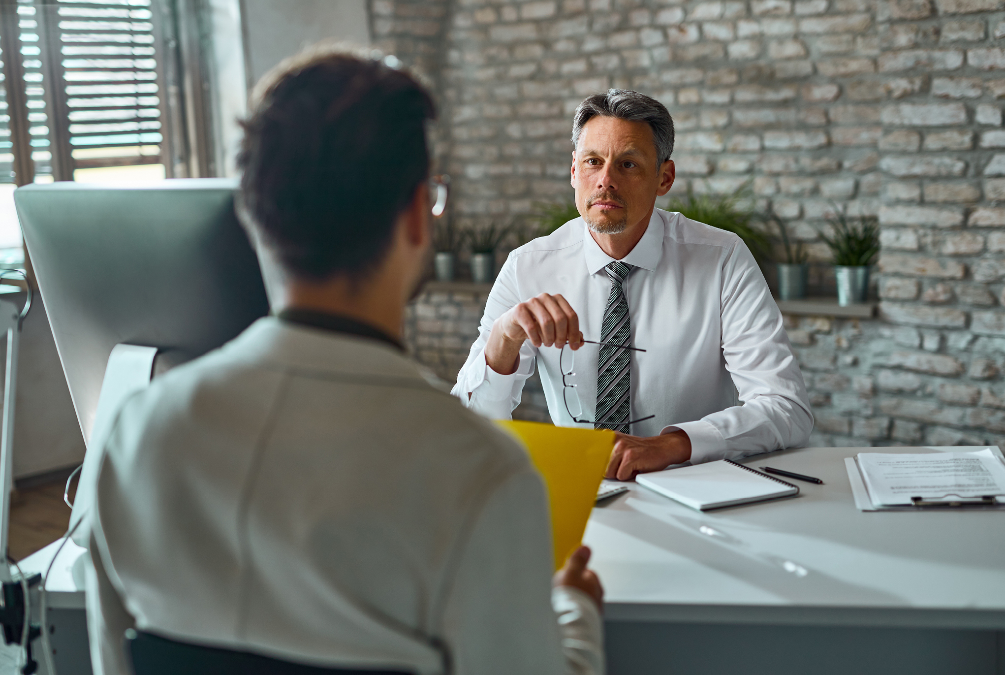 man sits across desk from another man in discussion