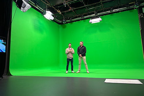 2 men stand in a green screen studio
